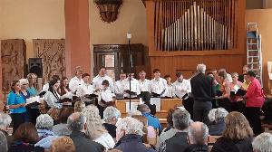 Der gemischte Chor des MGV singverein Freiheit beim Sommerkonzert 2024. Im Vordergrund Zuschauer, im Hintergrund die Orgel der evangelischen Stadtkirche.