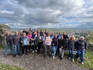 Ein Gruppenbild vor einer hügeligen Landschaft mit blauem Himmel und weißen Wolken.