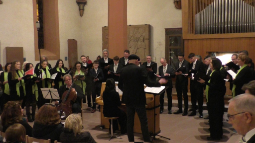 Ein gemischter Chor singt begleitet von einem Mann mit Chello und einer Frau am Klavier.