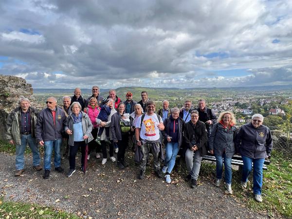 Gruppenbild der Ausflügler nach Weinsberg vor einer hügeligen Landschaft mit Dorf im Hintergrund.